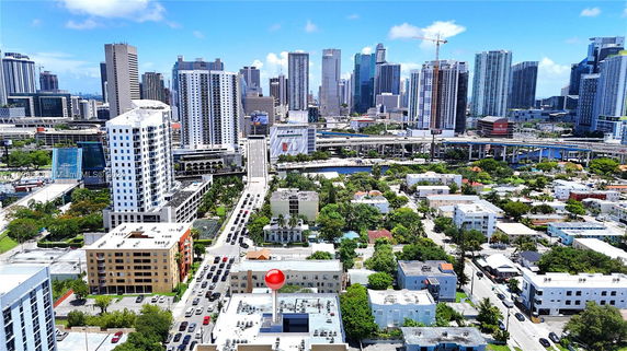 Panoramic view of city buildings with roads and green areas.