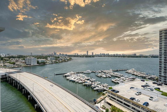Panoramic view of a waterfront cityscape with a bridge and marina.