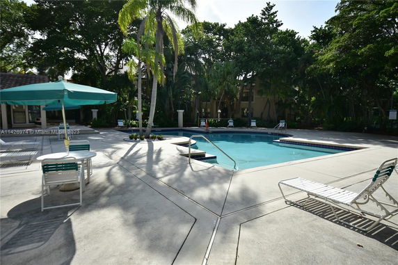 Outdoor swimming pool area with lounge chairs and umbrellas.