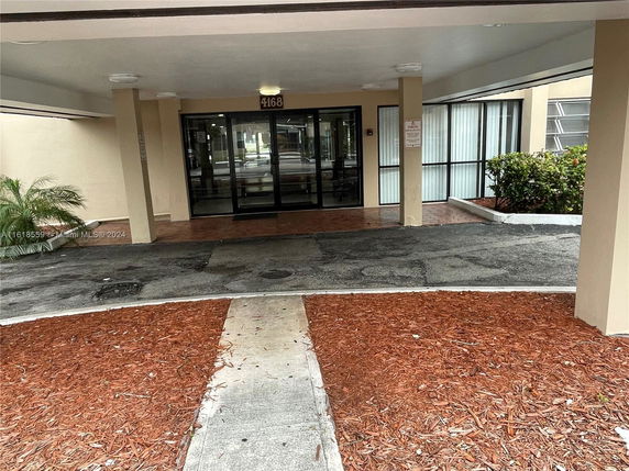 Front view of a building entrance with glass doors and covered walkway.