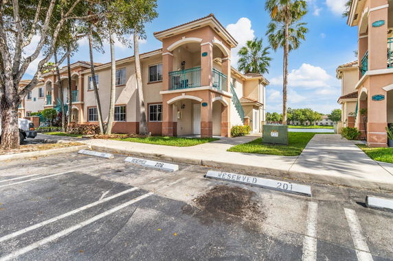 Front view of a two-story residential building with balconies and designated parking spaces.