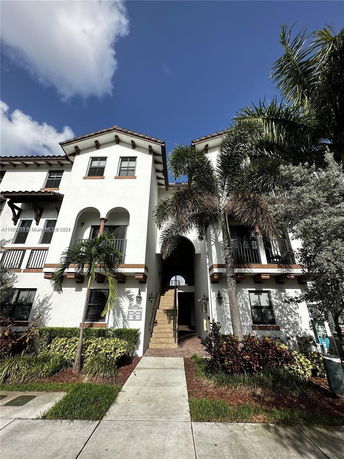 Front view of a multi-story building with a central staircase and arched entrance.