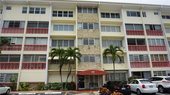 Front view of a multi-story residential building with balconies and entrance canopy.