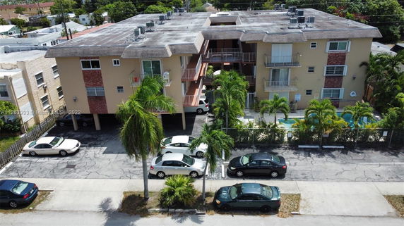 Front view of a multi-story residential building with parking area and balconies.
