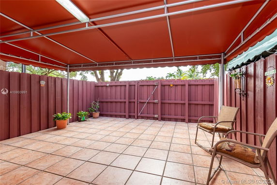 Covered outdoor patio area with tiled flooring and wooden fencing.