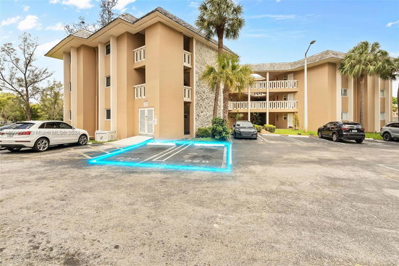 Front view of a multi-story building with adjacent parking spaces in front.