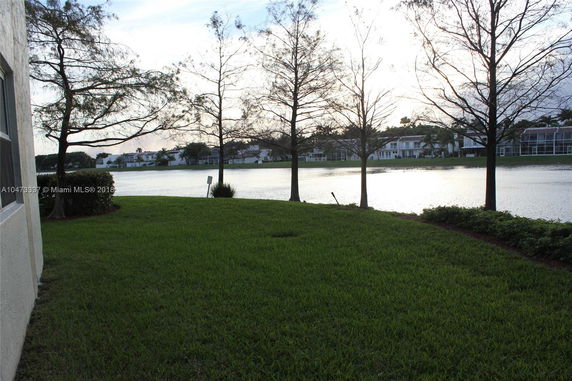 View of a lakeside area with trees and distant buildings across the water.