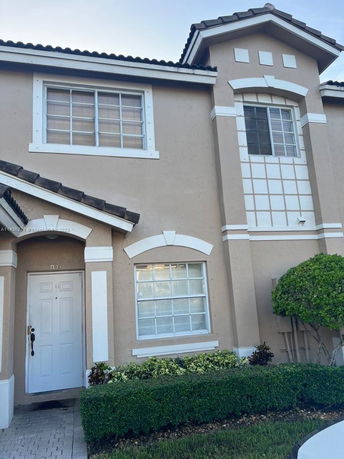 Front view of a two-story house with decorative window frames and a white entrance door.