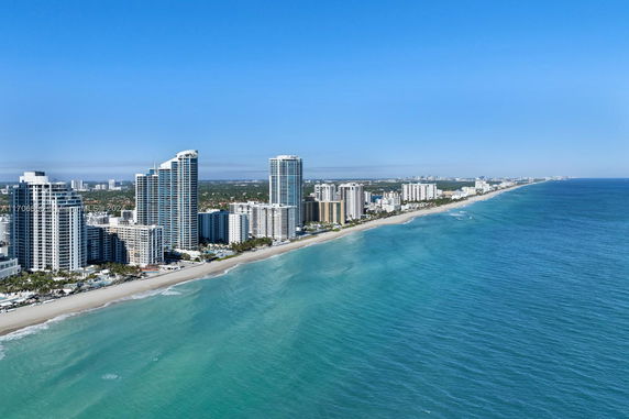 Aerial view of beachfront high-rise buildings along a coastline.