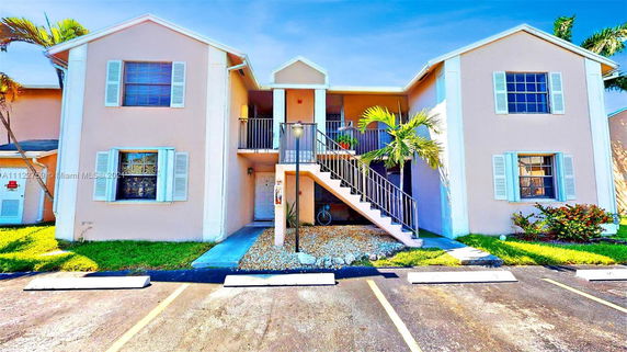 Front view of a two-story building with an exterior staircase and blue shutters on the windows.