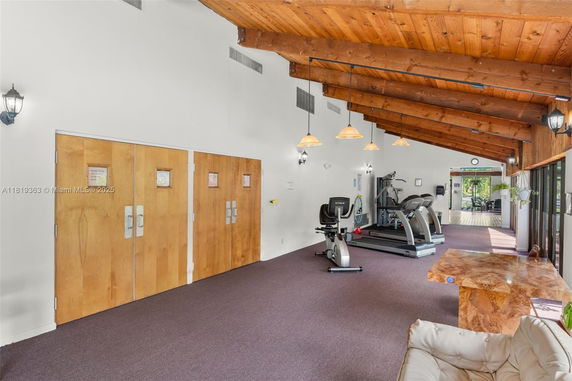 Interior of a gym area with exercise equipment and wooden ceiling.