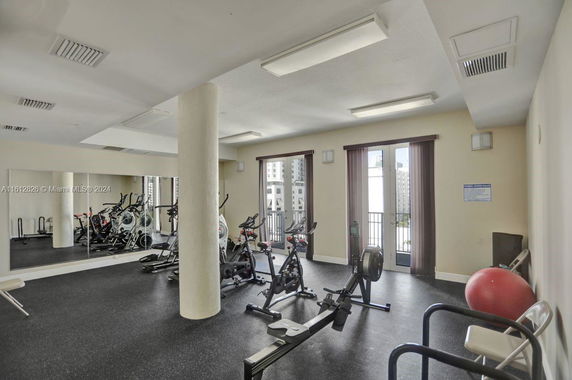 Indoor gym area with exercise equipment and mirrored wall.