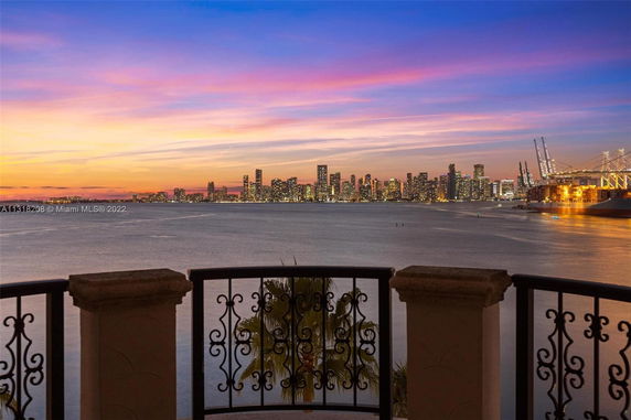 Panoramic view of a city skyline across a body of water during sunset.