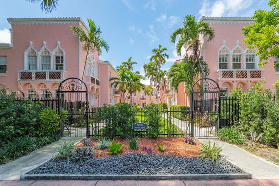 Front view of a two-story pink building with decorative windows and gated entrance.
