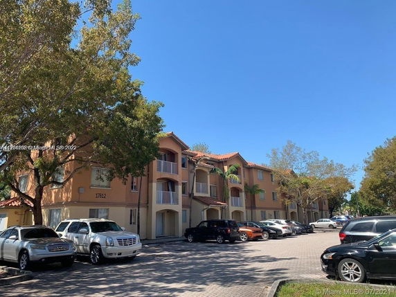 Front view of a residential building complex with multiple stories and parked cars.