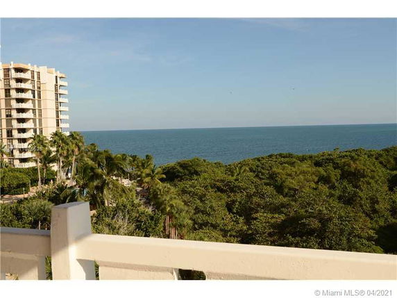 Panoramic view from a building showing the ocean and surrounding greenery.