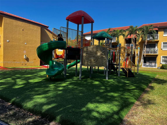 Outdoor play area with slides and climbing structures next to a residential building.