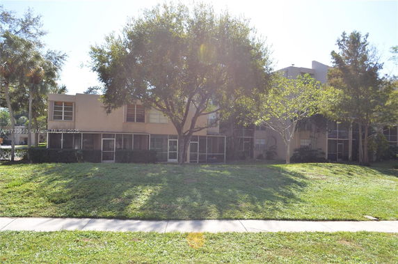 Front view of a two-story residential building with a screened porch and windows.