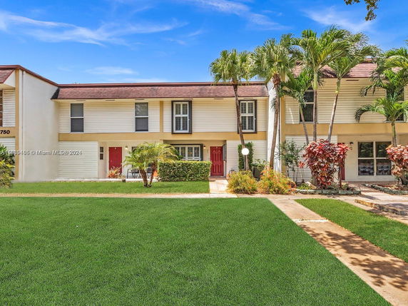 Front view of a two-story townhouse with a red door and adjacent garage.