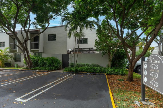 Front view of a two-story building with a flat roof and a parking area in front.