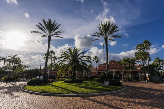 Front view of a building with palm trees and a circular driveway.
