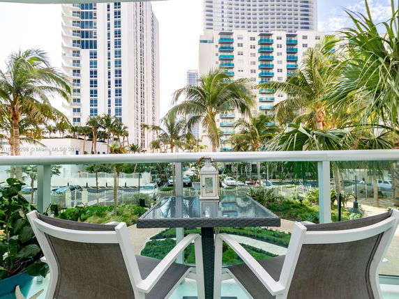 View from a balcony overlooking several high-rise buildings with palm trees in the foreground.
