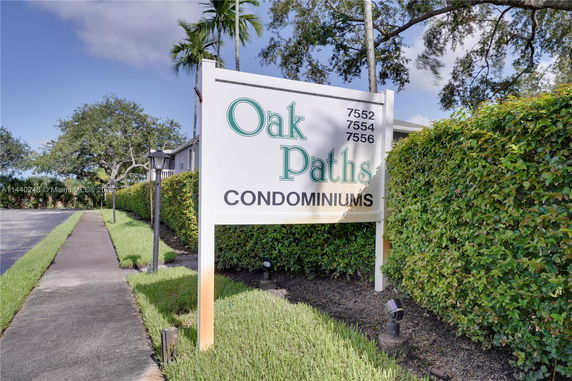 Sign for Oak Paths Condominiums with greenery and pathway.