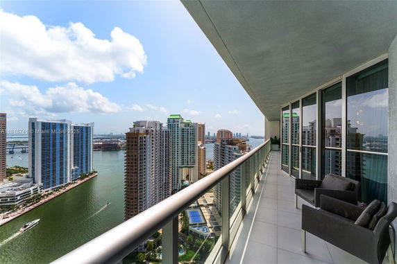 High-rise balcony with panoramic view of city buildings and waterway.