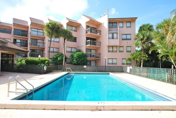 View of a multi-story building with a swimming pool in front.