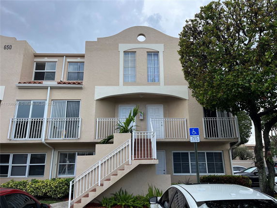Front view of a multi-story building with balconies and a stairway entrance.