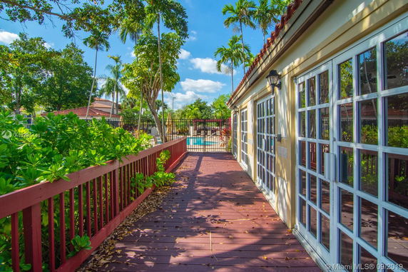 Side view of a house with large glass doors and a fenced pool area.
