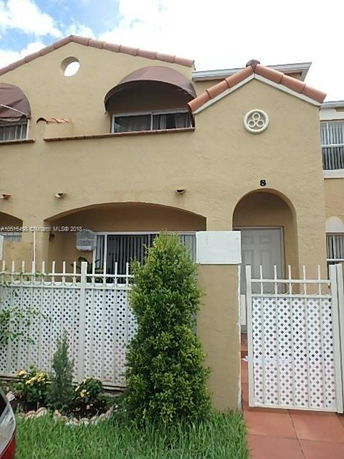 Front view of a two-story house with arched windows and terracotta roof tiles.