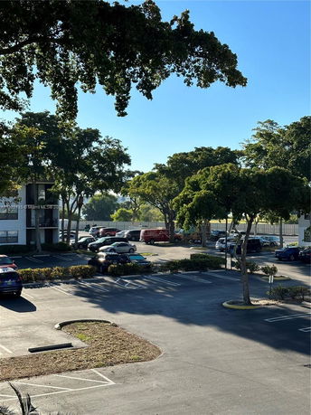View of a parking lot with cars and surrounding trees.