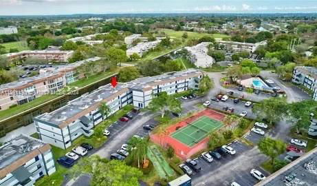 Panoramic view of residential buildings with a tennis court and parking area.
