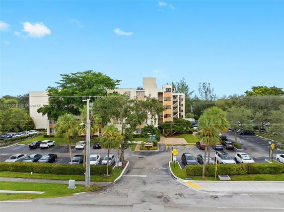 Front view of a multi-story apartment building with parking area in front.