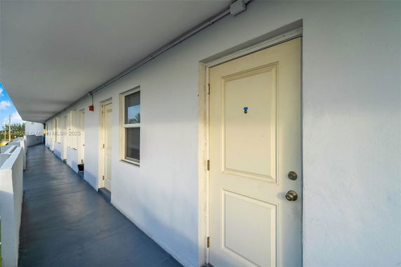 Exterior corridor with multiple doors and windows on a building.