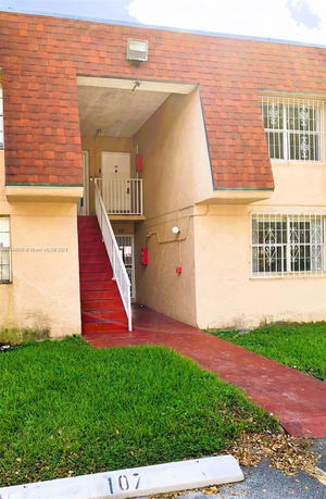 Front view of a two-story building with exterior stairs leading to upper level.