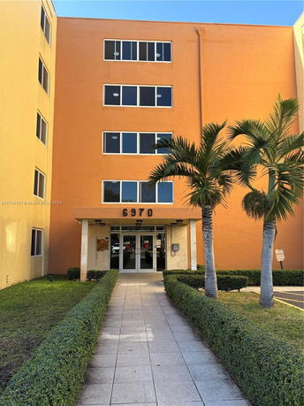 Front view of a multi-story building with an entrance pathway and the number 6970 visible above the door.
