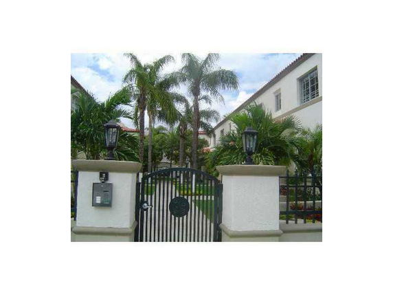 Front view of a house with a gated entrance and palm trees.