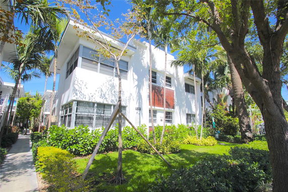 Front view of a two-story building with large windows and surrounding greenery.