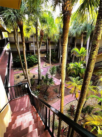 View of a multi-story building courtyard with palm trees and a staircase.