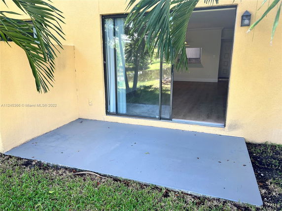 Front view of a house with large sliding glass doors leading to a small concrete patio.