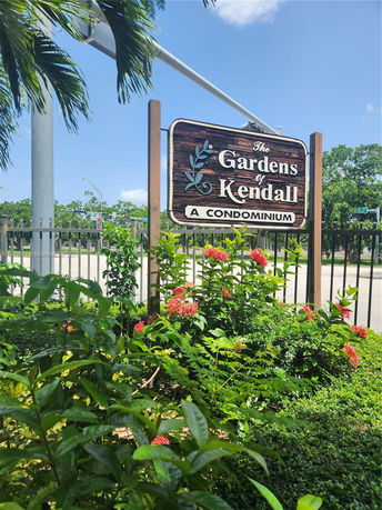 Sign for 'The Gardens of Kendall, A Condominium' surrounded by plants.
