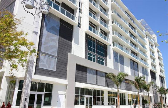 Front view of a multi-story modern building with large windows and balconies.