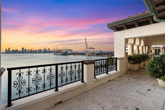 Panoramic view from a balcony overlooking the water and city skyline at sunset.