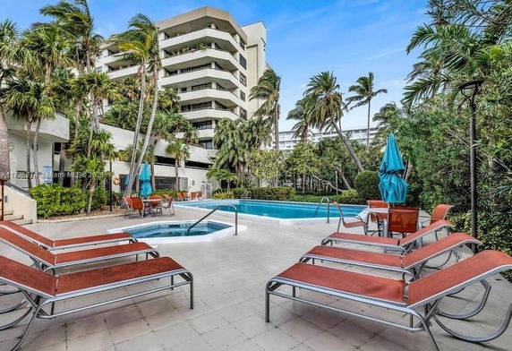 Outdoor area with a swimming pool and lounge chairs near a multi-story building.