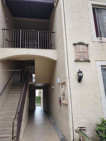 Entrance view of a multi-story building with a staircase and balcony.