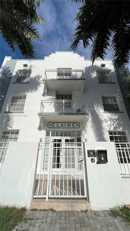 Front view of a multi-story building with balconies and a gated entrance.