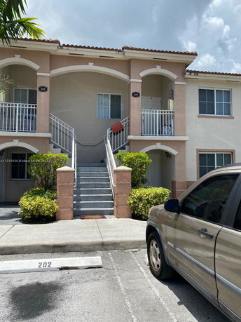 Front view of a two-story residential building with external stairs and arched balconies.