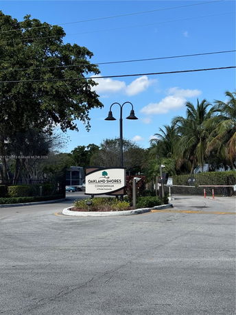 Entrance view of Oakland Shores condominium with surrounding greenery.